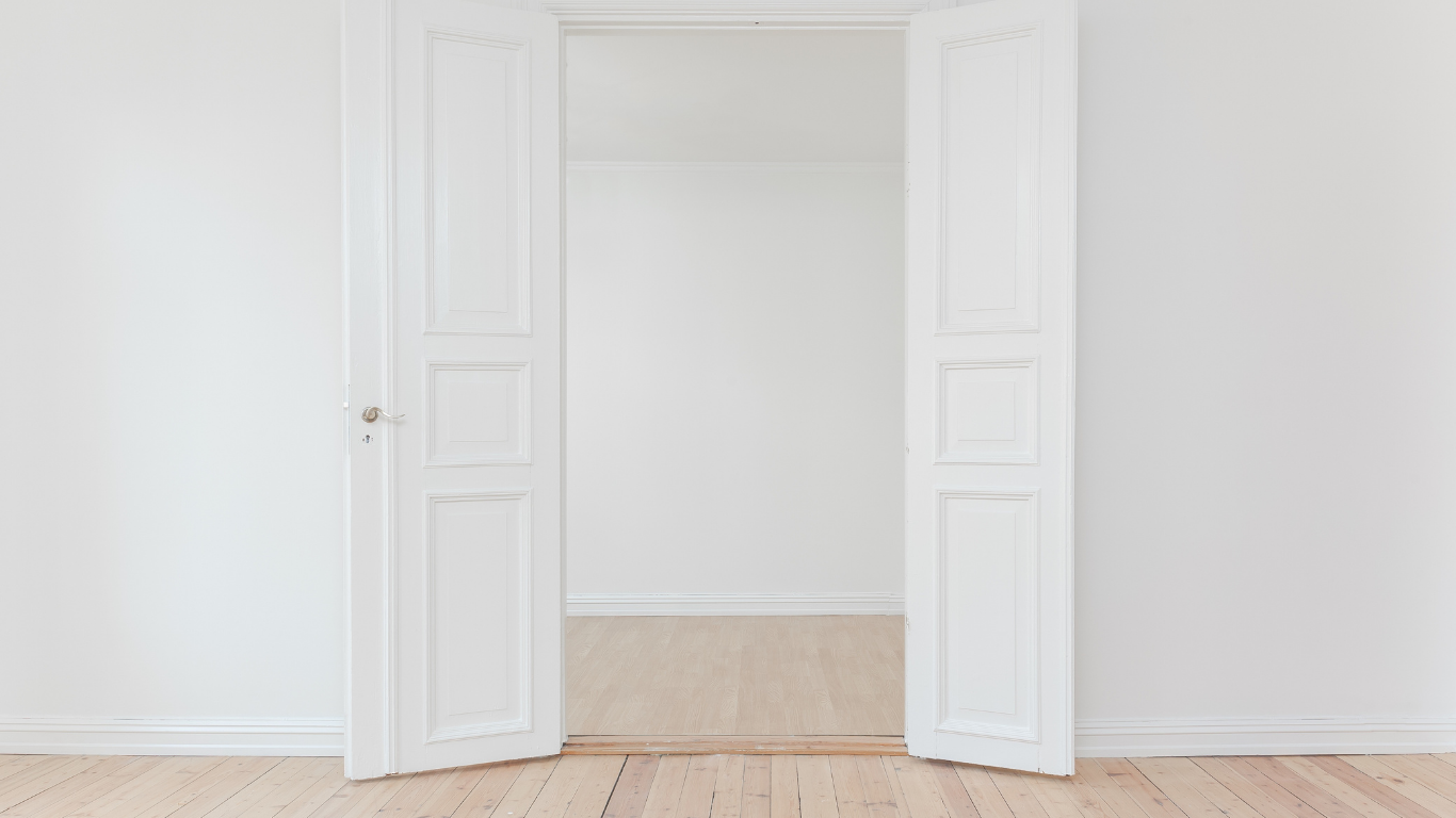 Open white double doors into a bright home with wooden floors